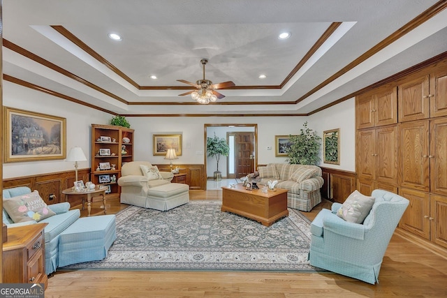 living area featuring crown molding, a wainscoted wall, ceiling fan, and a tray ceiling