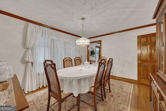 dining space featuring crown molding, baseboards, an inviting chandelier, and light wood-type flooring