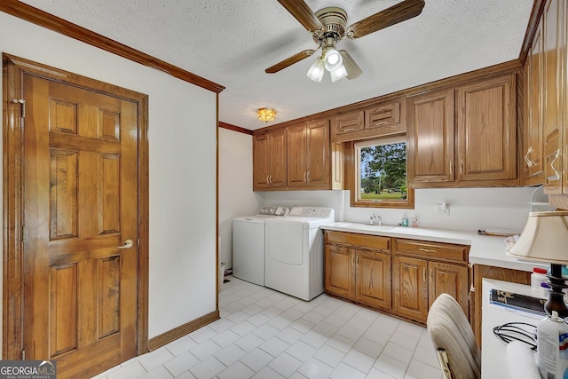 clothes washing area featuring a ceiling fan, cabinet space, a sink, ornamental molding, and washer and clothes dryer