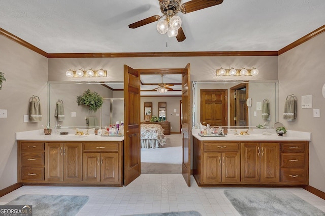 ensuite bathroom featuring crown molding, a ceiling fan, baseboards, and two vanities