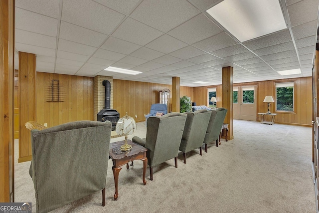 interior space featuring carpet, a wood stove, wood walls, and a paneled ceiling