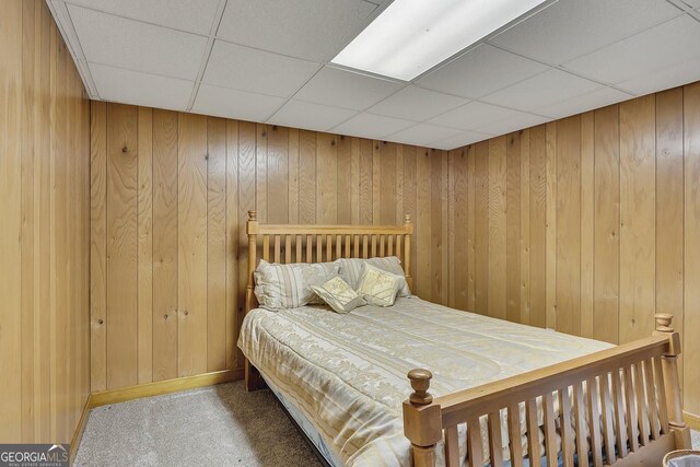 carpeted bedroom featuring a paneled ceiling and wooden walls
