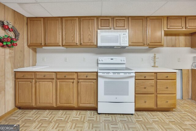 kitchen with brown cabinetry, light countertops, and white appliances