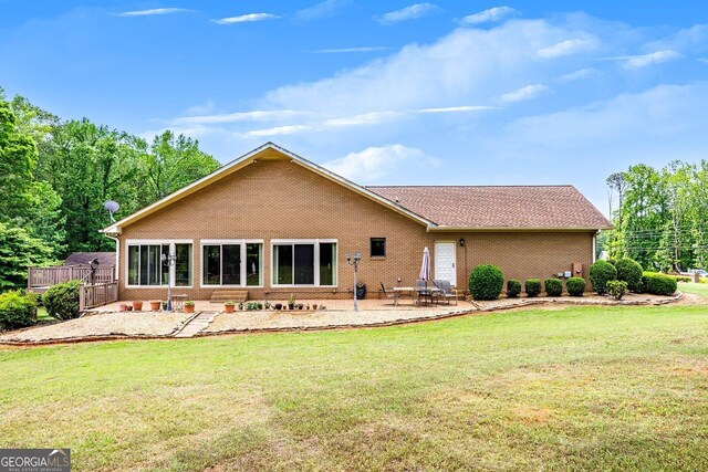 back of house featuring a patio, a yard, and brick siding