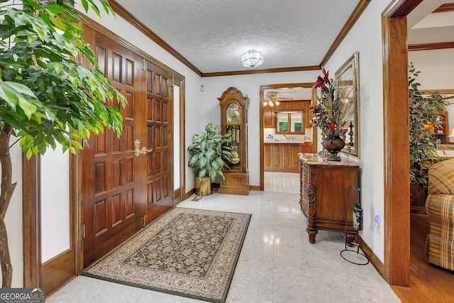 entryway with crown molding, a textured ceiling, and baseboards
