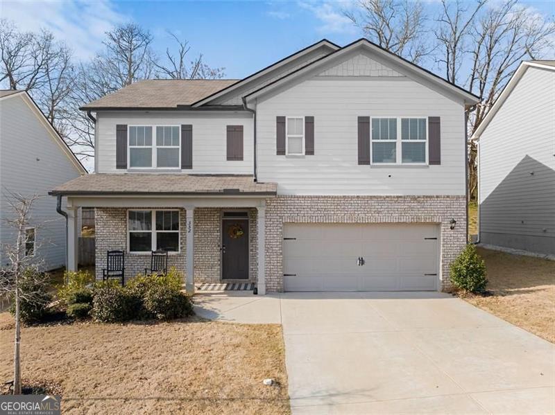 view of front of house with covered porch, an attached garage, driveway, and brick siding