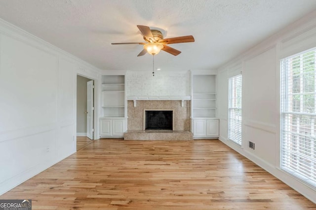5611 Manassas Run, Stone Mountain, GA 30087 - unfurnished living room with crown molding, built in shelves, a ceiling fan, light wood-type flooring, and visible vents
