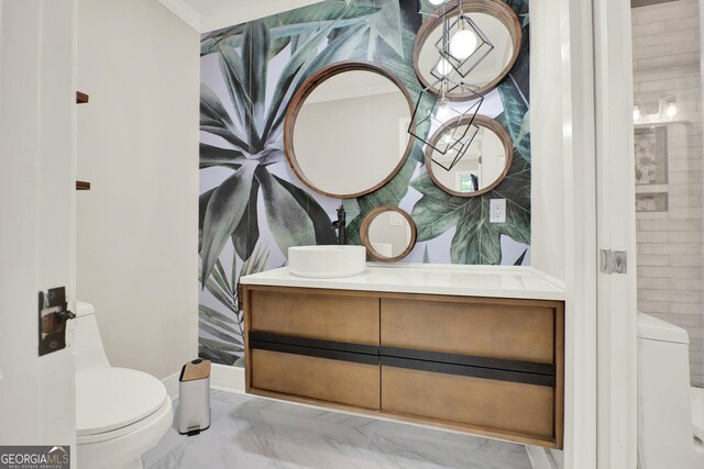 bathroom featuring toilet, ornamental molding, marble finish floor, and vanity