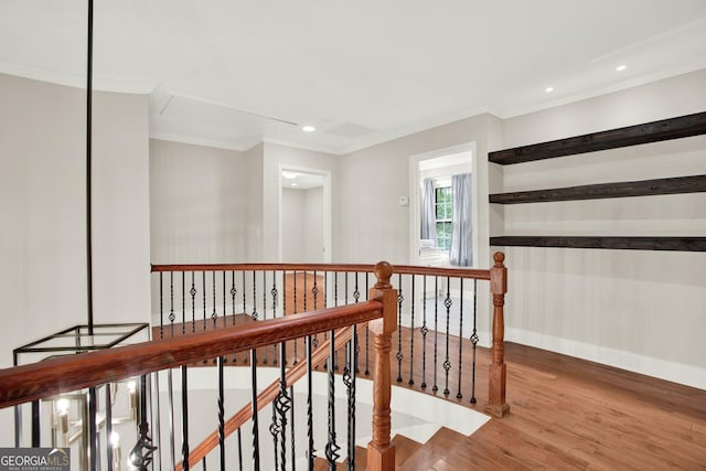 hallway with ornamental molding, wood finished floors, baseboards, recessed lighting, and an upstairs landing