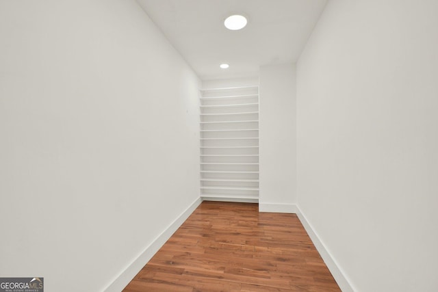 hallway featuring baseboards, recessed lighting, and wood finished floors