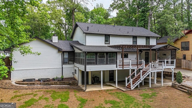 rear view of property featuring a chimney, a wooden deck, a sunroom, a patio area, and a pergola