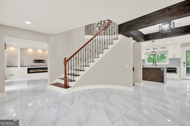 staircase with a tiled fireplace, marble finish floor, baseboards, and visible vents