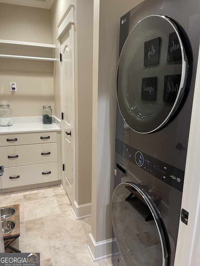 2220 Cambridge Hill Ct, Dacula, GA 30019 - laundry area featuring stacked washer / dryer, baseboards, and light stone finish flooring
