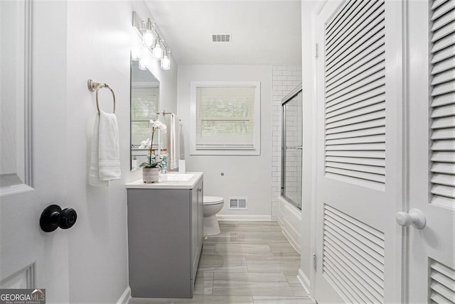 bathroom with toilet, vanity, baseboards, and combined bath / shower with glass door