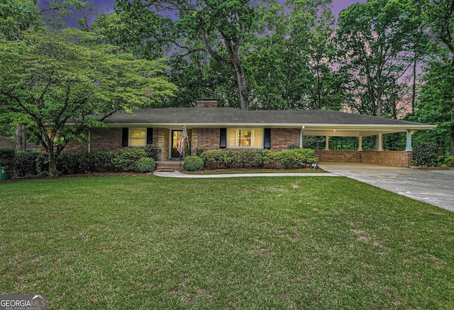 ranch-style house featuring driveway, a chimney, a front yard, an attached carport, and brick siding