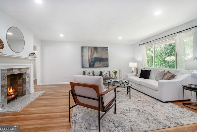 living room with a fireplace, light wood-style floors, recessed lighting, and baseboards