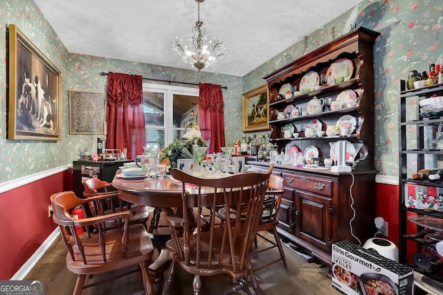 dining room featuring a notable chandelier, a wainscoted wall, baseboards, wallpapered walls, and wood finished floors