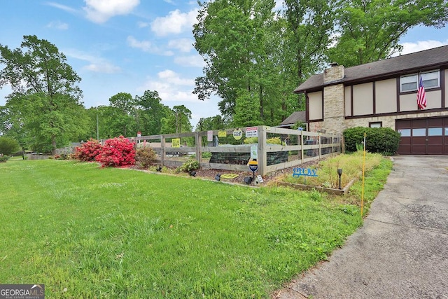 view of yard featuring an attached garage, driveway, and a garden