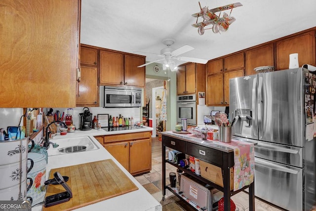 kitchen with brown cabinets, ceiling fan, a sink, light countertops, and stainless steel appliances