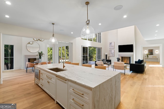 490 Mount Paran Rd, Atlanta, GA 30327 - kitchen with a lit fireplace, a sink, light stone countertops, light wood-type flooring, and a center island with sink
