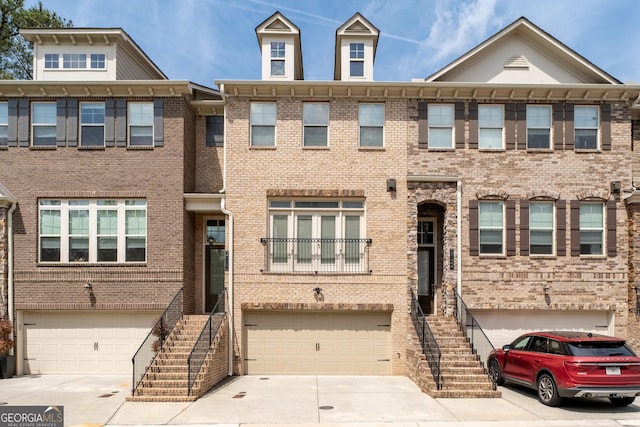 multi unit property with a garage, driveway, and stairway