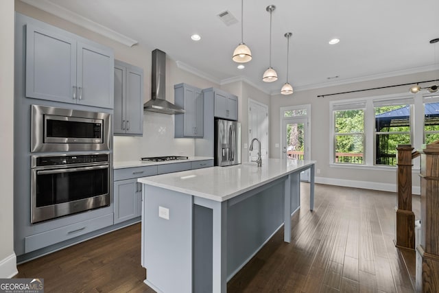 kitchen featuring wall chimney range hood, gray cabinets, visible vents, crown molding, and stainless steel appliances
