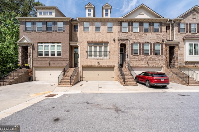 townhome / multi-family property featuring a garage, stairway, and concrete driveway