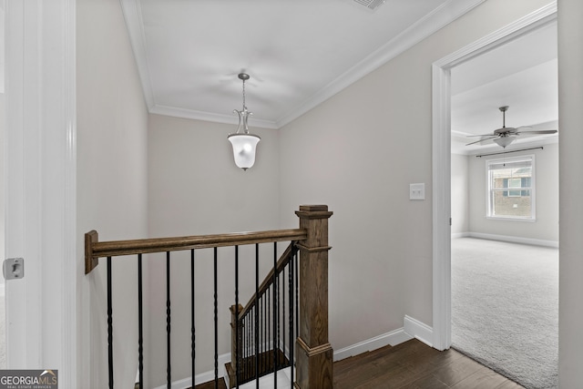 stairs with crown molding, carpet floors, a ceiling fan, baseboards, and wood finished floors