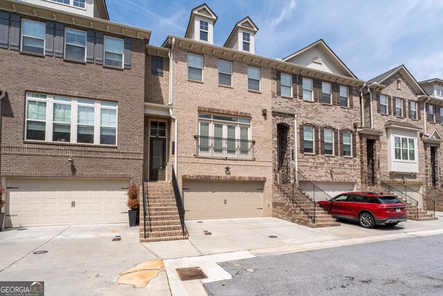 view of property with brick siding, a garage, driveway, and stairway
