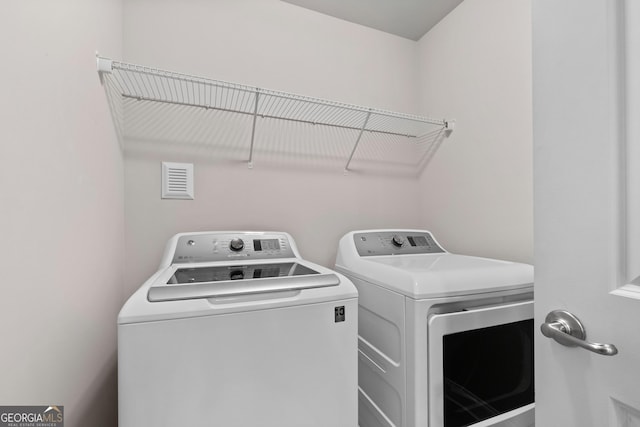 laundry room with laundry area, separate washer and dryer, and visible vents