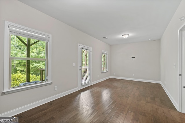 spare room featuring baseboards, dark wood-style floors, and visible vents