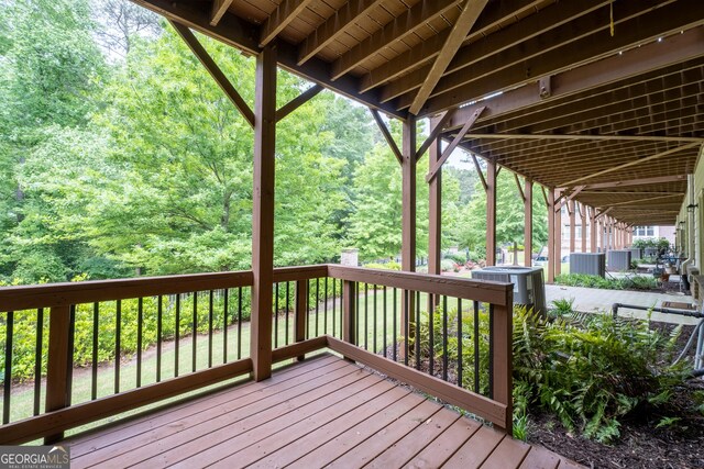 wooden terrace featuring a wooded view and central AC unit