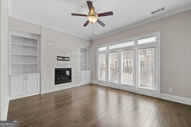 unfurnished living room featuring visible vents, built in features, wood finished floors, ceiling fan, and a high end fireplace