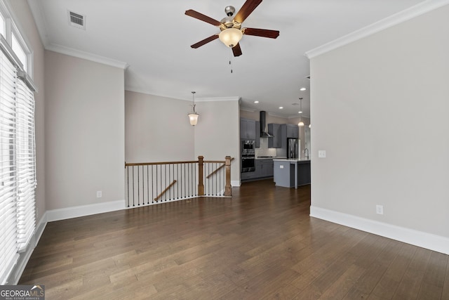 interior space with ornamental molding, a ceiling fan, dark wood-type flooring, and visible vents