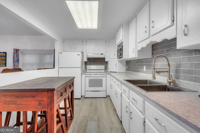 kitchen with decorative backsplash, white appliances, white cabinetry, under cabinet range hood, and a sink