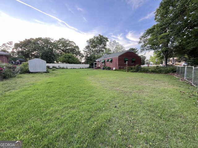 view of yard with a fenced backyard, an outdoor structure, and a shed