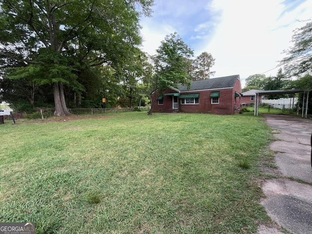 view of yard featuring a detached carport, fence, and driveway
