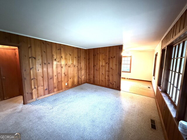 unfurnished room featuring baseboards, wood walls, and visible vents