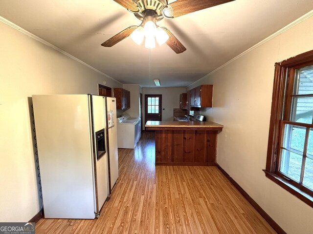 kitchen featuring light wood-style floors, ceiling fan, washer and dryer, and white fridge with ice dispenser