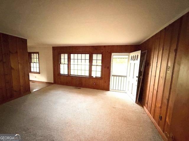 carpeted empty room with wood walls and visible vents