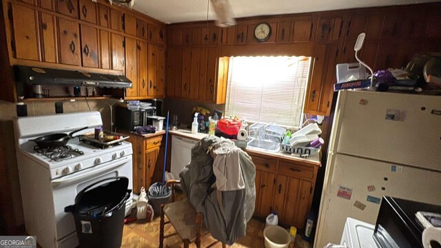 kitchen featuring brown cabinetry, light countertops, ventilation hood, and white appliances