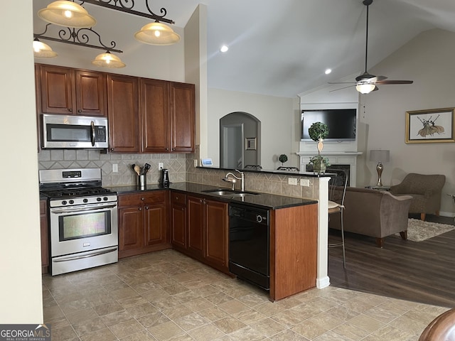 kitchen featuring a sink, a peninsula, open floor plan, a ceiling fan, and appliances with stainless steel finishes