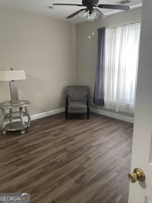 unfurnished room featuring dark wood-style flooring, a ceiling fan, and baseboards