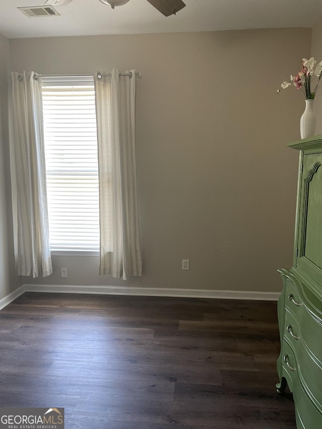 unfurnished room featuring ceiling fan, visible vents, dark wood-style floors, and a wealth of natural light