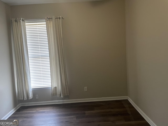 spare room featuring baseboards and dark wood finished floors