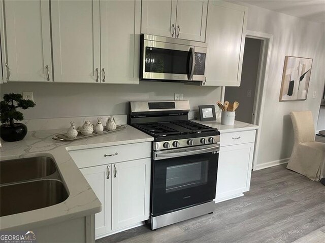 2135 Niskey Lake Rd, Atlanta, GA 30331 - kitchen with appliances with stainless steel finishes, light wood-style floors, light stone counters, and white cabinetry