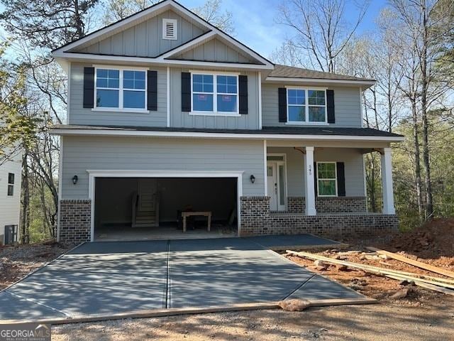 craftsman house with a garage, brick siding, board and batten siding, a porch, and driveway