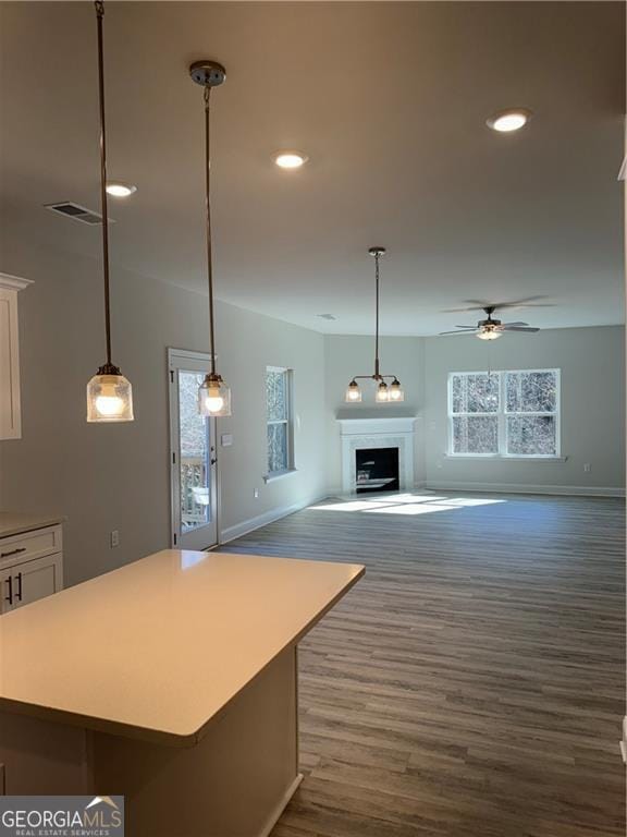 unfurnished living room featuring ceiling fan, dark wood finished floors, baseboards, and visible vents