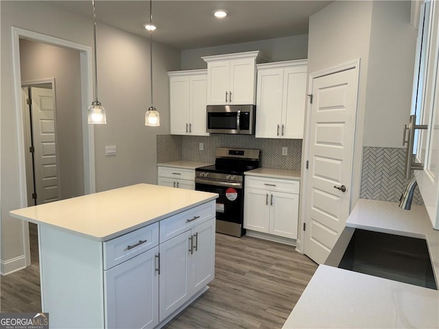 kitchen with decorative backsplash, wood finished floors, white cabinets, and stainless steel appliances