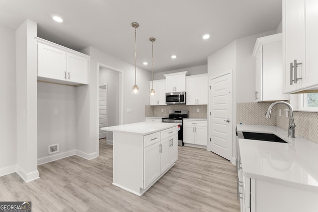 kitchen with white cabinets, appliances with stainless steel finishes, a sink, light wood-style flooring, and a kitchen island